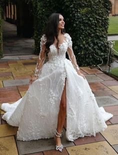 a woman in a white wedding dress standing on a brick walkway with her legs spread out