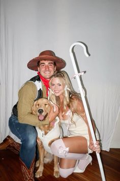 a man and woman pose with a dog in front of a white backdrop wearing cowboy hats