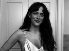 a black and white photo of a woman with long hair in a satin dress posing for the camera