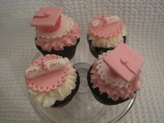 three cupcakes with pink and white frosting on top are arranged in the shape of graduation caps