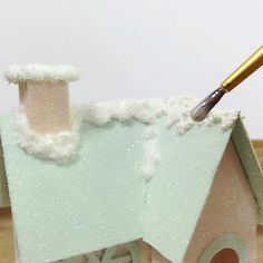 a house with snow on the roof and a paintbrush in it's mouth