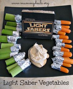 some carrots and celery sticks are on a black tray with lightsabers