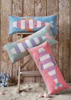 two decorative pillows sitting on top of a wooden chair next to a stuffed animal toy