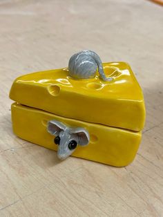 a toy mouse sitting on top of a yellow piece of furniture that is shaped like a box