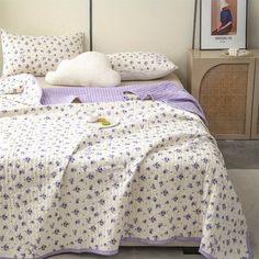 a bed with purple and white bedspread on it