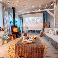 a living room with wicker furniture and a projector screen on the wall above it