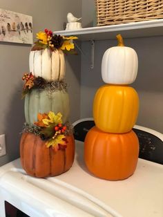 three pumpkins stacked on top of each other in front of a stovetop oven