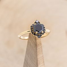 a black diamond ring sitting on top of a wooden stand in front of a beige background