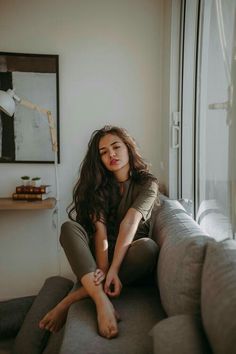 a woman sitting on top of a couch next to a window