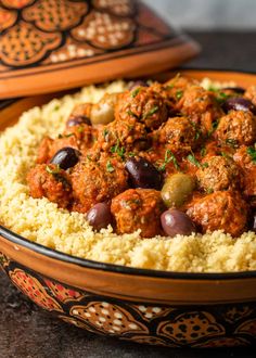 a bowl filled with meatballs and olives on top of couscouse