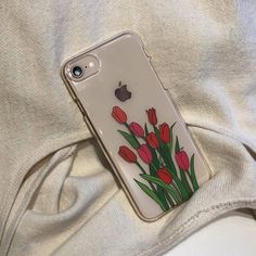 an iphone case with flowers painted on it sitting on top of a white sheet covered bed