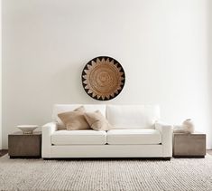 a living room with a white couch and coffee table in front of a wall hanging on the wall