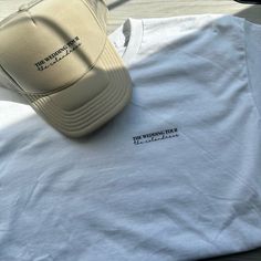 a white t - shirt with a hat sitting on top of it