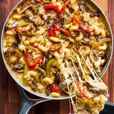 a pan filled with pasta and vegetables on top of a wooden table