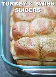 there is a glass casserole dish with turkey and swiss sliders in it