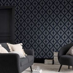 two black chairs sitting next to each other in front of a wall with geometric designs on it