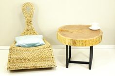 a wicker chair next to a table with a cup on it and a blue pillow