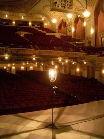 an empty theatre with lights on the floor and chandeliers hanging from the ceiling