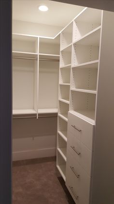 an empty walk in closet with white shelving