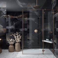 a bathroom with marble walls and flooring, two vases filled with flowers in front of the shower