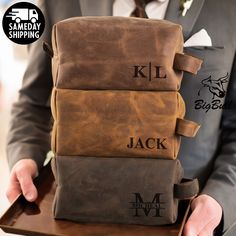 a man in a suit holding three brown bags with initials on them and the words kl, jack written across each bag