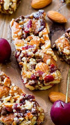 some fruit and nuts are sitting on a wooden board next to almonds, cherries, and other fruits