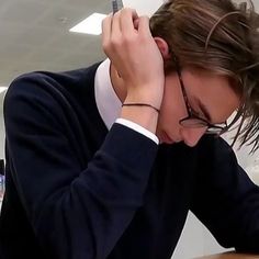 a man sitting at a desk with his head in his hands and writing on a piece of paper