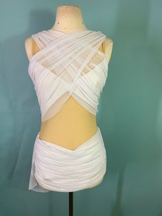 the back of a white dress on a mannequin headdress with sheer fabric draped over it