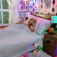 a doll is laying in her bed surrounded by toys