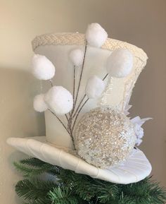 a white hat with pom - poms hanging from the side on top of a christmas tree