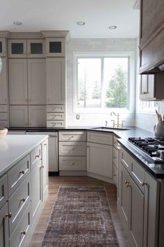 a kitchen with white cabinets and an area rug in front of the stove top oven