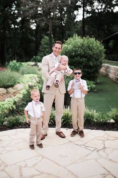 a man in a suit and two young boys are standing on a stone walkway outside