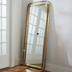 a large mirror sitting on top of a wooden floor next to a wall mounted door