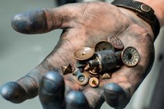 a person's hand holding lots of different types of buttons and screws in their palm