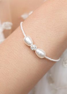 a close up of a person's arm wearing a bracelet with pearls on it