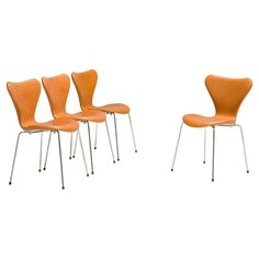 four orange chairs sitting next to each other on top of a white surface with metal legs