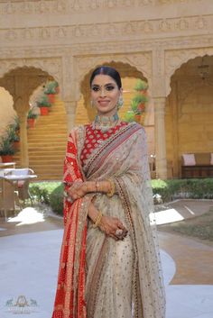 a woman in a white and red bridal outfit posing for the camera with her hands on her hips