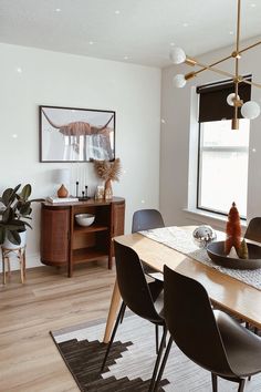 a dining room table with black chairs and an art piece on the wall behind it