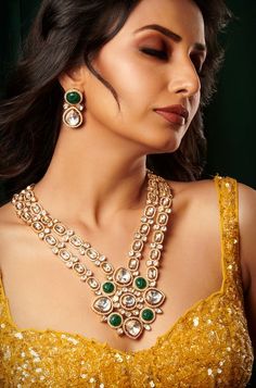 Introducing an exquisite double-layer Kundan necklace adorned with radiant Kundan stones, accompanied by matching earrings, all set in mixed metal with opulent 22kt gold plating, offering an enchanting blend of tradition and elegance. Finish: 22KT Gold Plating Material: Brass, Kundan Color: Gold, Green & White Size: Free Size, Adjustable Closure Type: Draw String Box Contains: 1 Necklace, 1 Pair of Earrings Festive 22k Gold Emerald Necklace For Celebration, Elegant Gold Kundan Necklace With Meenakari, Gold Chandbali Bridal Necklace With 17 Jewels, Gold Temple Jewelry Bridal Necklace With Gemstones, Gold Jewelry Sets For Diwali Reception, Festive Emerald Necklace With Intricate Design, Festive Yellow Gold Emerald Necklace For Celebration, Gold Temple Necklace With Stone Work For Reception, Gold Meenakari Jewelry For Reception