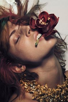 a woman with red hair and a flower on her head