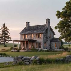 a stone house sits in the middle of a grassy field