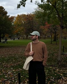 a man standing in the park holding a paper bag