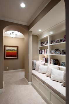 a living room filled with white couches and bookshelves next to a doorway