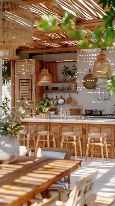 an outdoor kitchen and dining area with wicker chairs, wooden tables and hanging lights