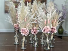 four vases with flowers and feathers in them sitting on a table next to each other