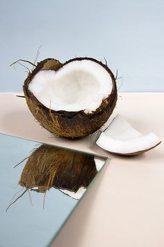 a half eaten coconut sitting on top of a table next to a knife and mirror