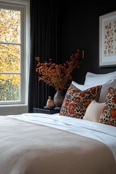 a bedroom with black walls, white bedding and orange pillows in front of a large window