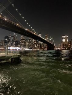 the city skyline is lit up at night as seen from the water's edge