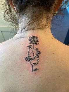 the back of a woman's neck with a rose tattoo on her left shoulder