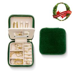 an open green case with jewelry in it on a white background next to a christmas wreath